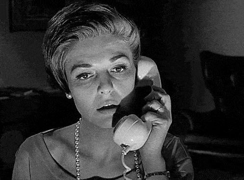 a woman is talking on a telephone with a surprised look on her face .