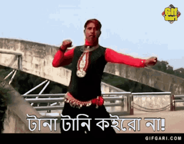 a man in a red and black outfit is dancing on a bridge in front of a sign that says gif gari.com