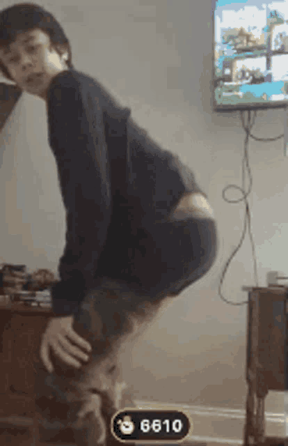 a boy is squatting down in front of a television with the number 6610 on the bottom