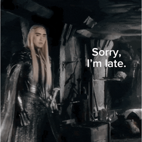 a man with long blonde hair is standing in a dark room with the words sorry i 'm late below him