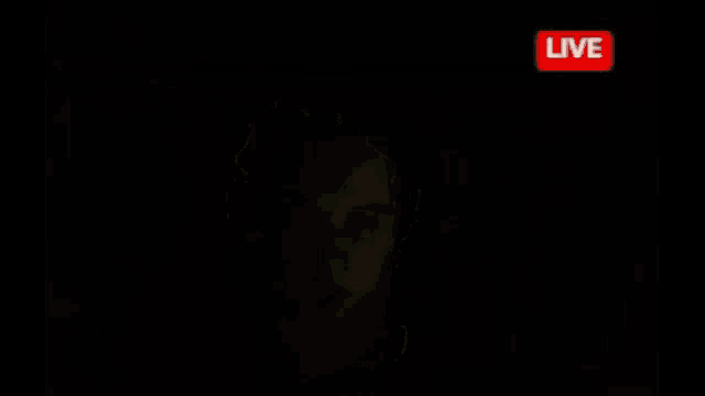 a man wearing headphones looks at the camera with a live sign in the corner