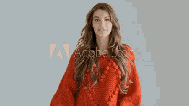 a woman in a red sweater is dancing in front of a gray wall .