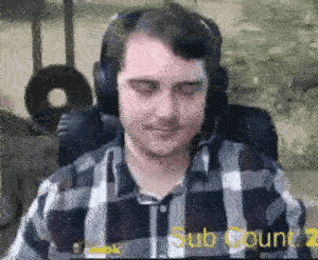 a man wearing headphones and a plaid shirt is sitting in front of a screen that says ' sub count 2 '