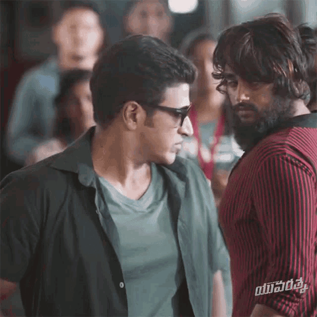 two men are standing next to each other and one has a sticker on his shirt that says ' vijay ' on it