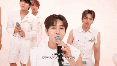 a group of young men are singing into microphones and one of them says aegyo
