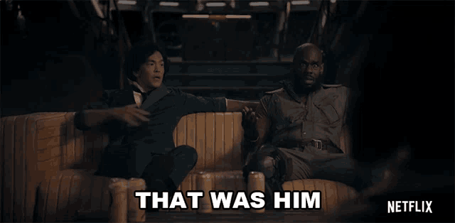 two men are sitting on a couch with the words that was him on the bottom