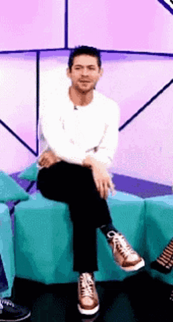 a man in a white shirt and black pants is sitting on a couch