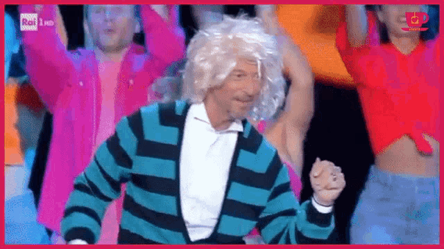 a man wearing a wig and a striped sweater is dancing on a stage with other people .