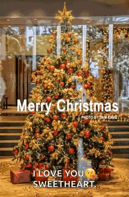 a christmas tree is decorated with red and gold ornaments and gifts and says merry christmas i love you sweetheart .