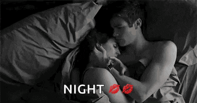 a black and white photo of a man and a woman hugging and kissing in bed .