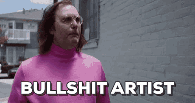a man wearing a pink turtleneck and glasses is standing in front of a white brick wall and says bullshit artist .