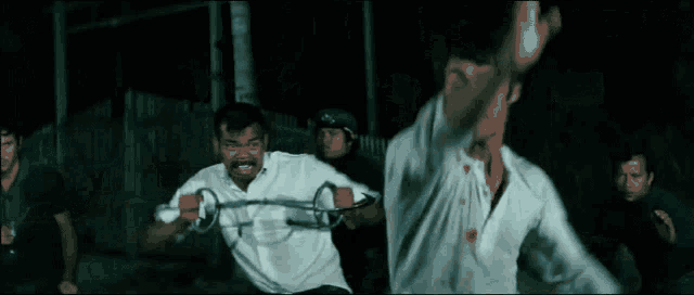 a group of men are fighting each other with swords in a dark room