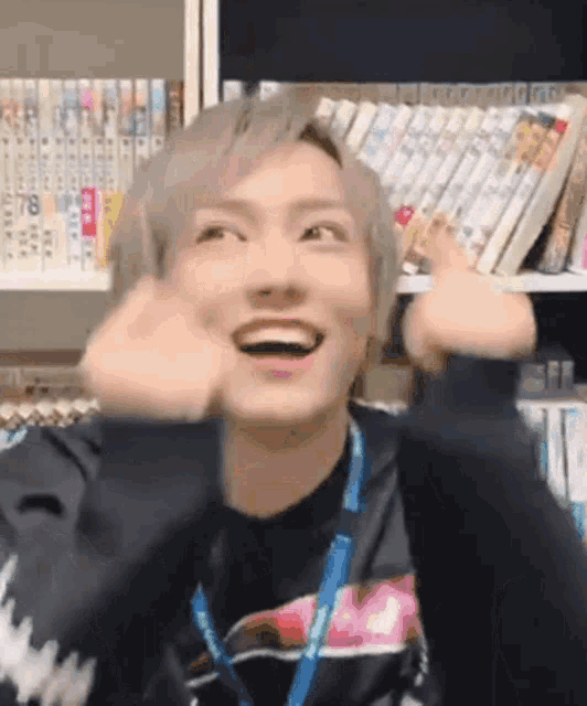 a young man is making a funny face in front of a bookshelf filled with books .