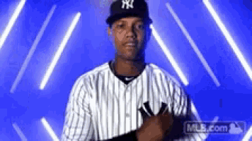 a man in a new york yankees uniform stands in front of a blue background