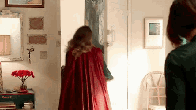 a woman in a red cape is standing in a hallway .