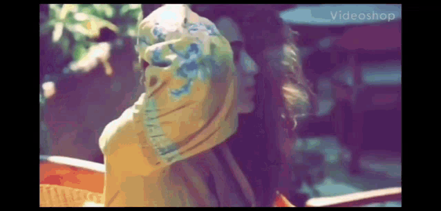 a woman in a yellow shirt is sitting in a chair with a scarf around her head .