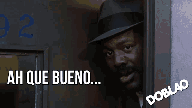 a man in a fedora is smiling with the words ah que bueno below him