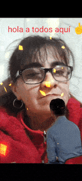 a woman wearing glasses and a red jacket with the words hola a todos aqui