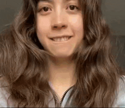 a close up of a woman 's face with long hair smiling .