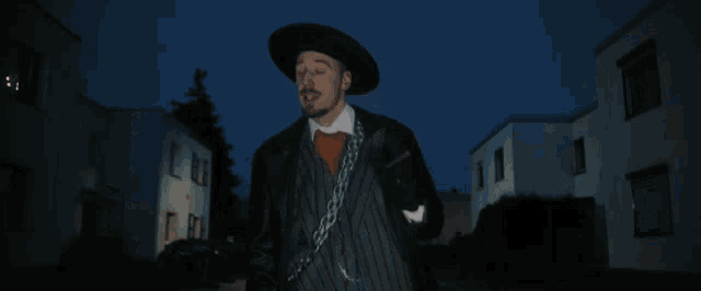 a man in a striped suit and hat is holding a chain around his neck