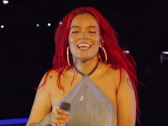 a woman with red hair and hoop earrings sings into a microphone