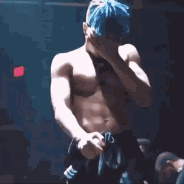 a shirtless man with blue hair and a necklace around his neck .
