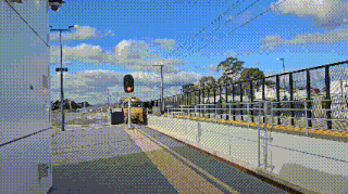 a yellow bus is stopped at a train station with a red light