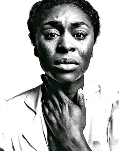 a black and white photo of a woman holding her hand to her neck .