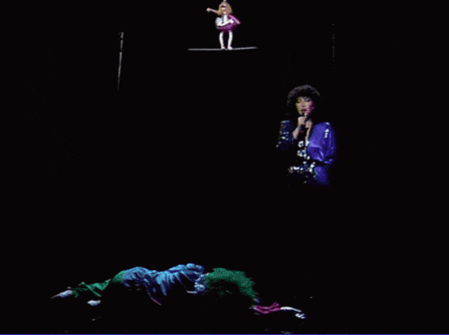a woman singing into a microphone while two clowns perform on a stage