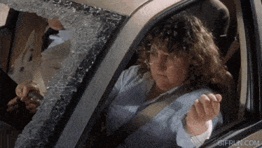 a woman is sitting in a car with a broken windshield and the website gifrun.com is visible