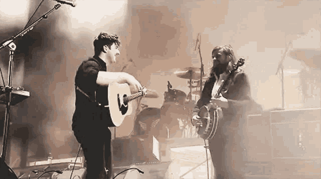 a man is playing an acoustic guitar and a woman is playing a banjo on stage .