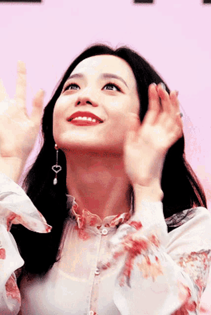 a woman wearing a floral shirt and earrings looks up at the sky