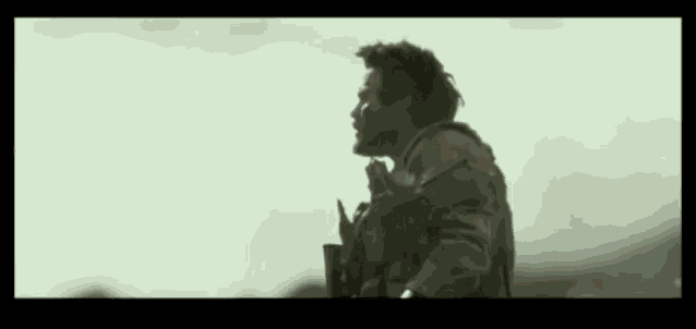a man in a military uniform holds a gun and looks to the side