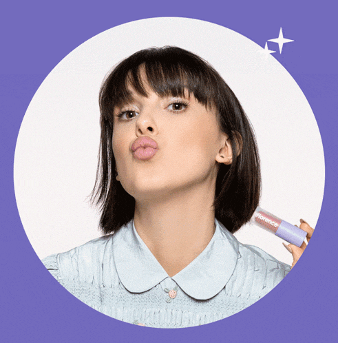 a woman in a blue shirt is holding a lip gloss that says florence on it