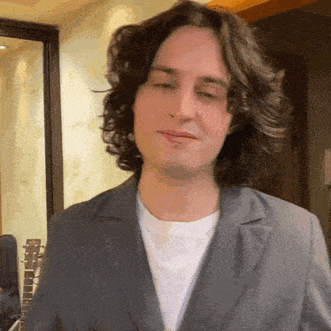 a man with long curly hair wearing a suit and a white shirt