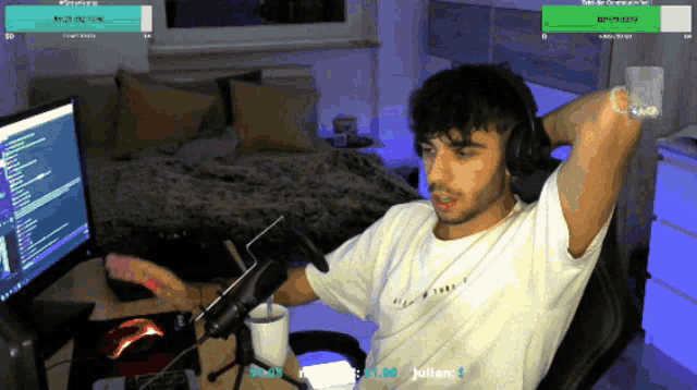 a man wearing headphones and a shirt that says julian sits in front of two computer monitors