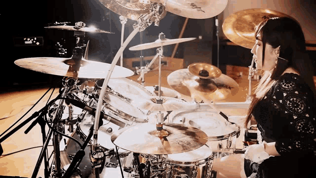 a woman is playing a drum set with a cymbal that says sabian