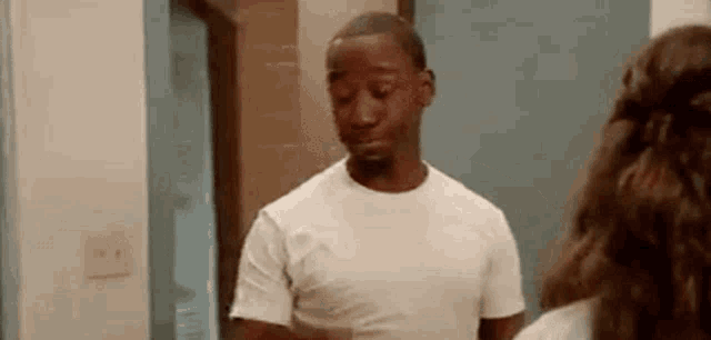 a man in a white shirt is standing in front of a woman in a bathroom .