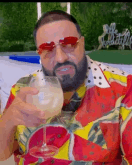 a man in a colorful shirt is holding a glass of wine .