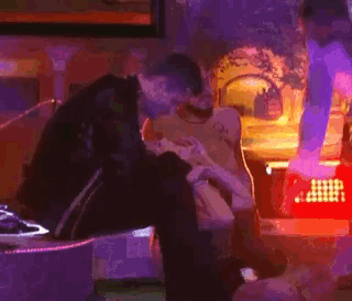 a group of people are sitting in a room and one of them is kissing another