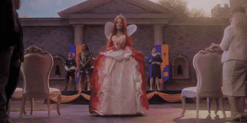 a woman in a red and white dress with a crown on her head stands on a stage
