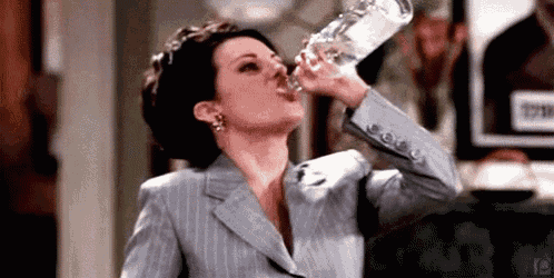 a woman is drinking water from a glass bottle .