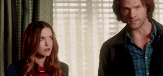 a man and a woman are standing next to each other in a room looking at each other .