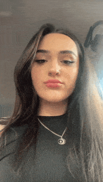 a woman wearing a black top and a silver necklace with a crescent moon pendant
