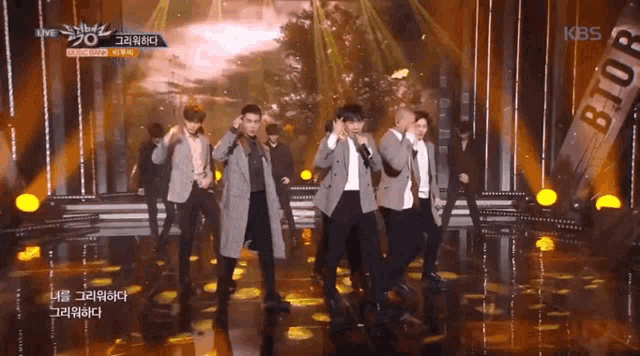 a group of men are dancing on a stage with a kbs logo in the background