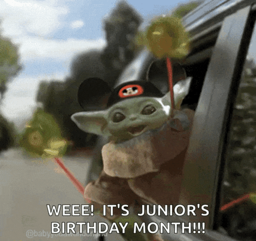 a baby yoda wearing a mickey mouse hat is holding lollipops out of a car window .