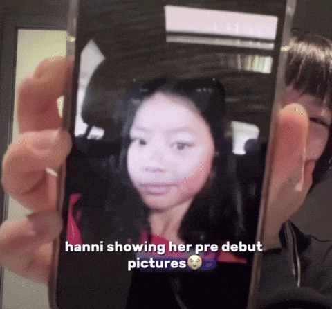 a person is holding a cell phone with a picture of a girl on it and the caption says hanni showing her pre debut pictures
