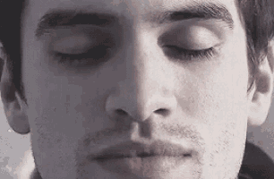 a close up of a man 's face with his eyes closed and a beard .