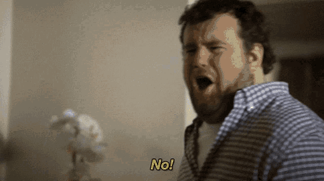 a man in a plaid shirt says " no " with his mouth open