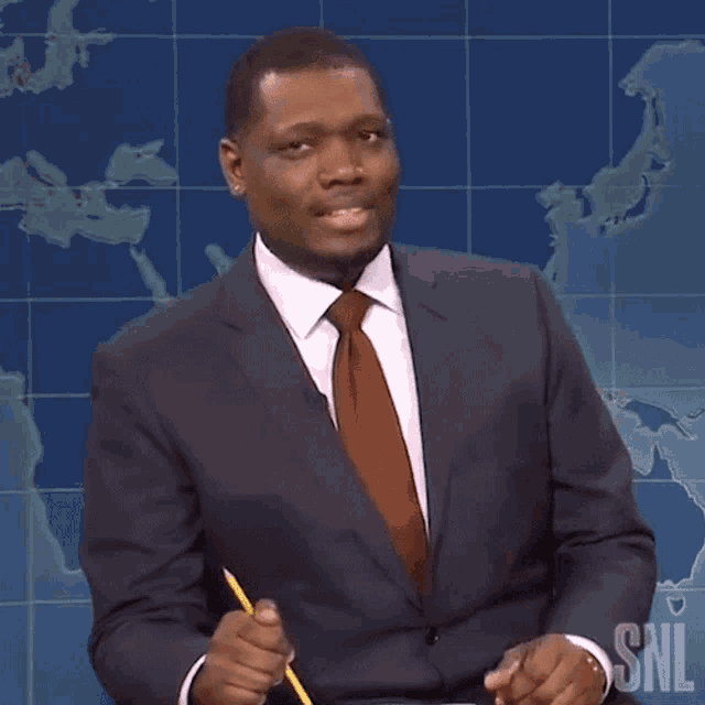 a man in a suit and tie holds a pencil in front of a snl map